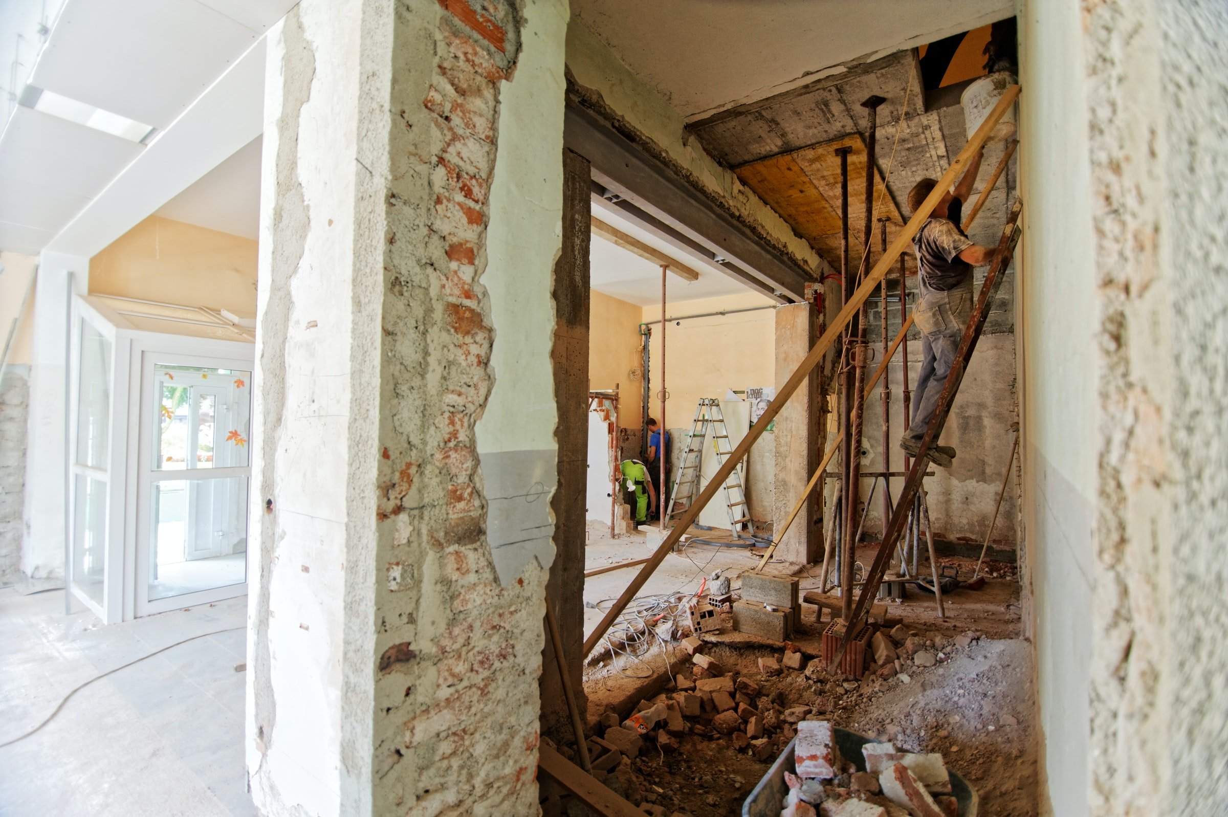 Construction workers work on renovating a building. The interior of an apartment under renovation with exposed brick and framing