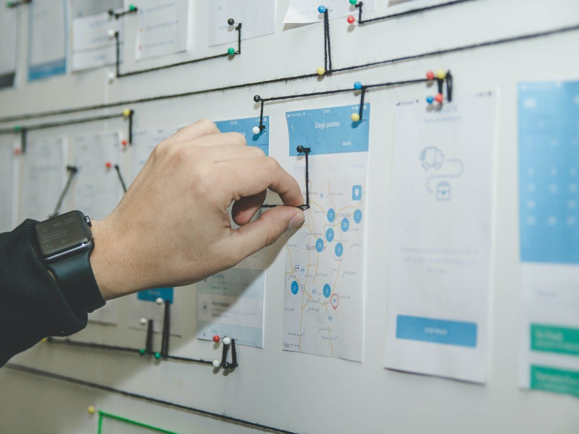 A hand pinning planning cards to a whiteboard
