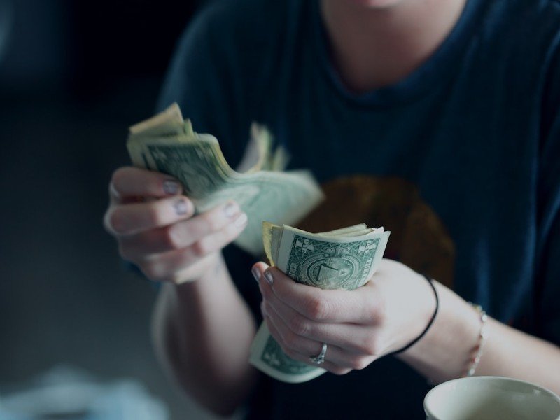 A person counting U.S. dollar bills by hand