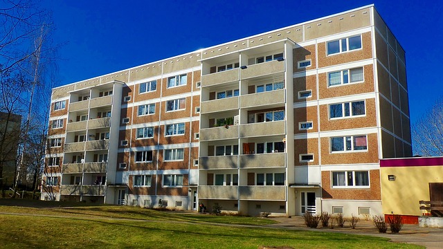 Five-story walk-up apartment building with balconies under a clear sky