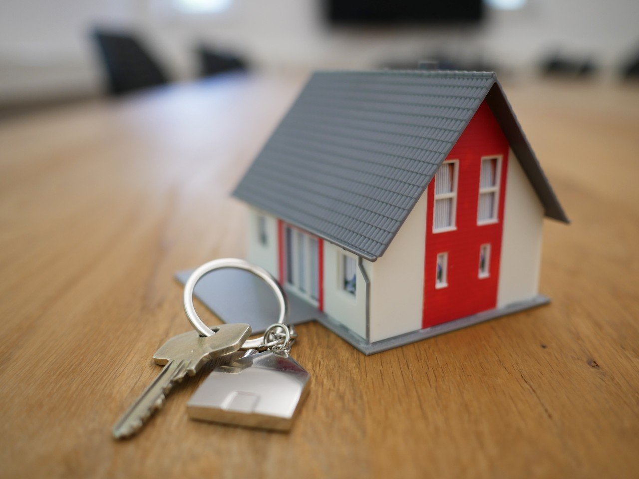 A miniature house and a key. A model house and a set of keys on a table