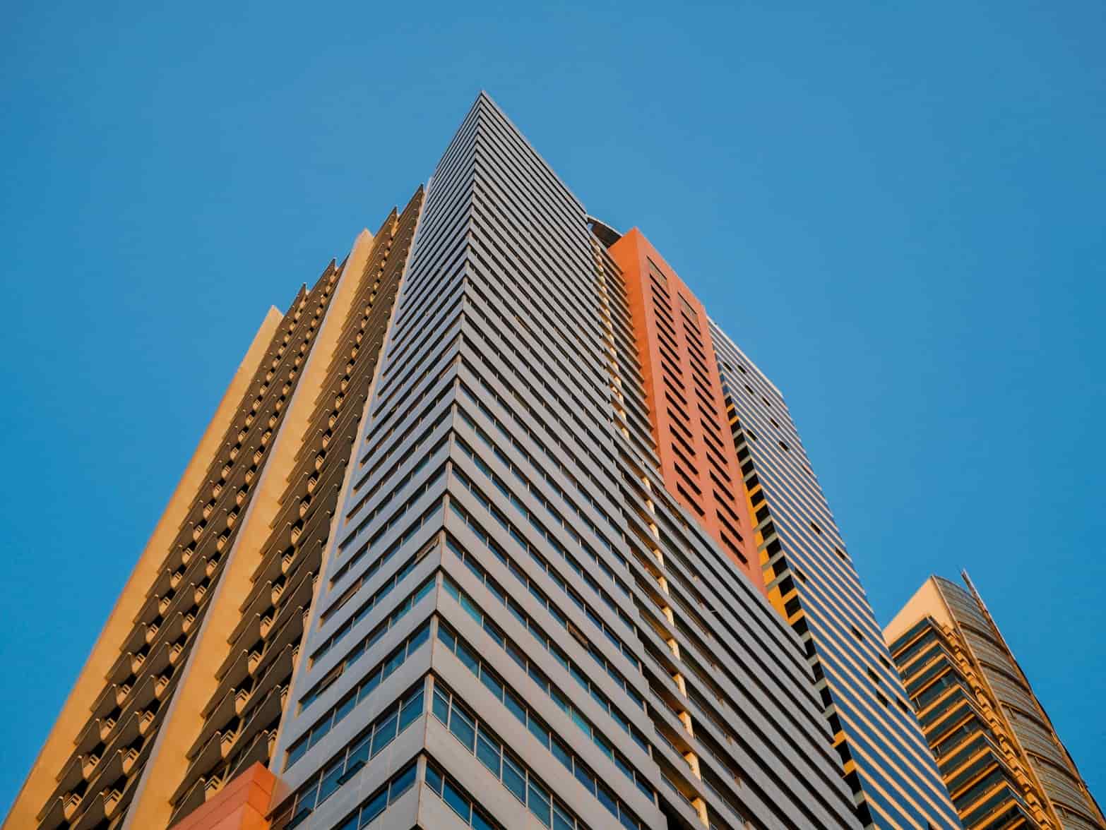 Looking up at a high-rise residential tower against a clear sky