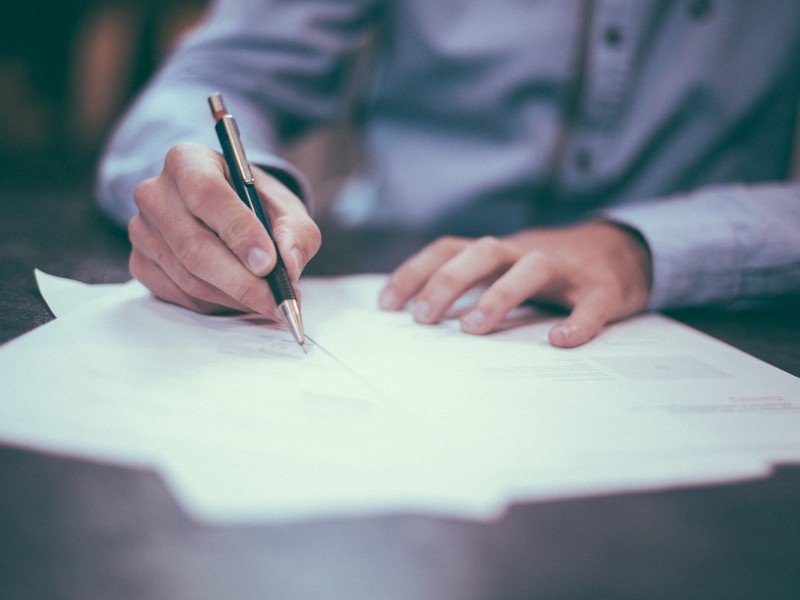 A person signing documents at a desk